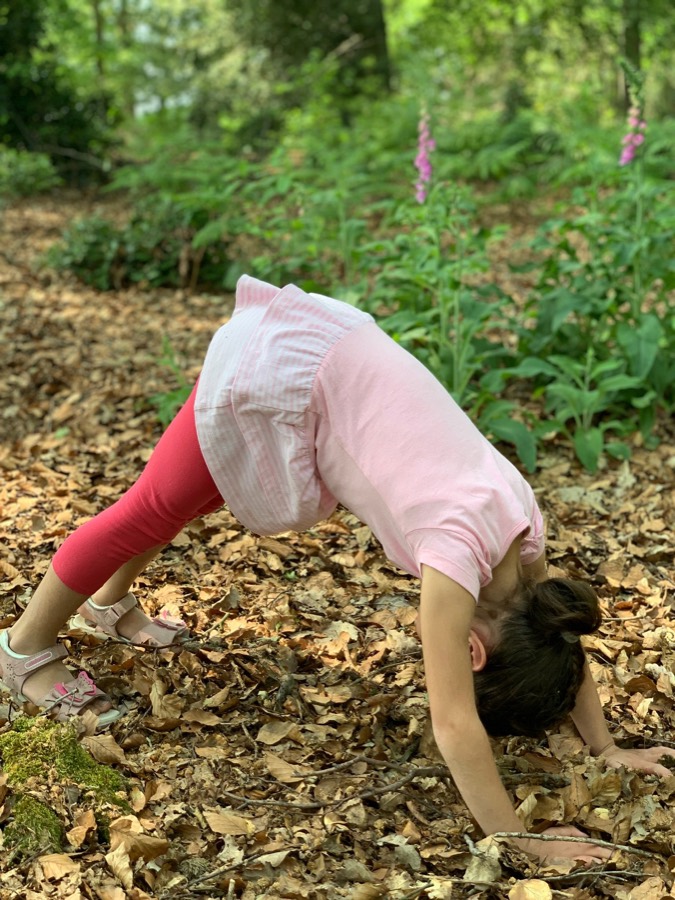 Kind übt eine Yoga-Haltung im Wald